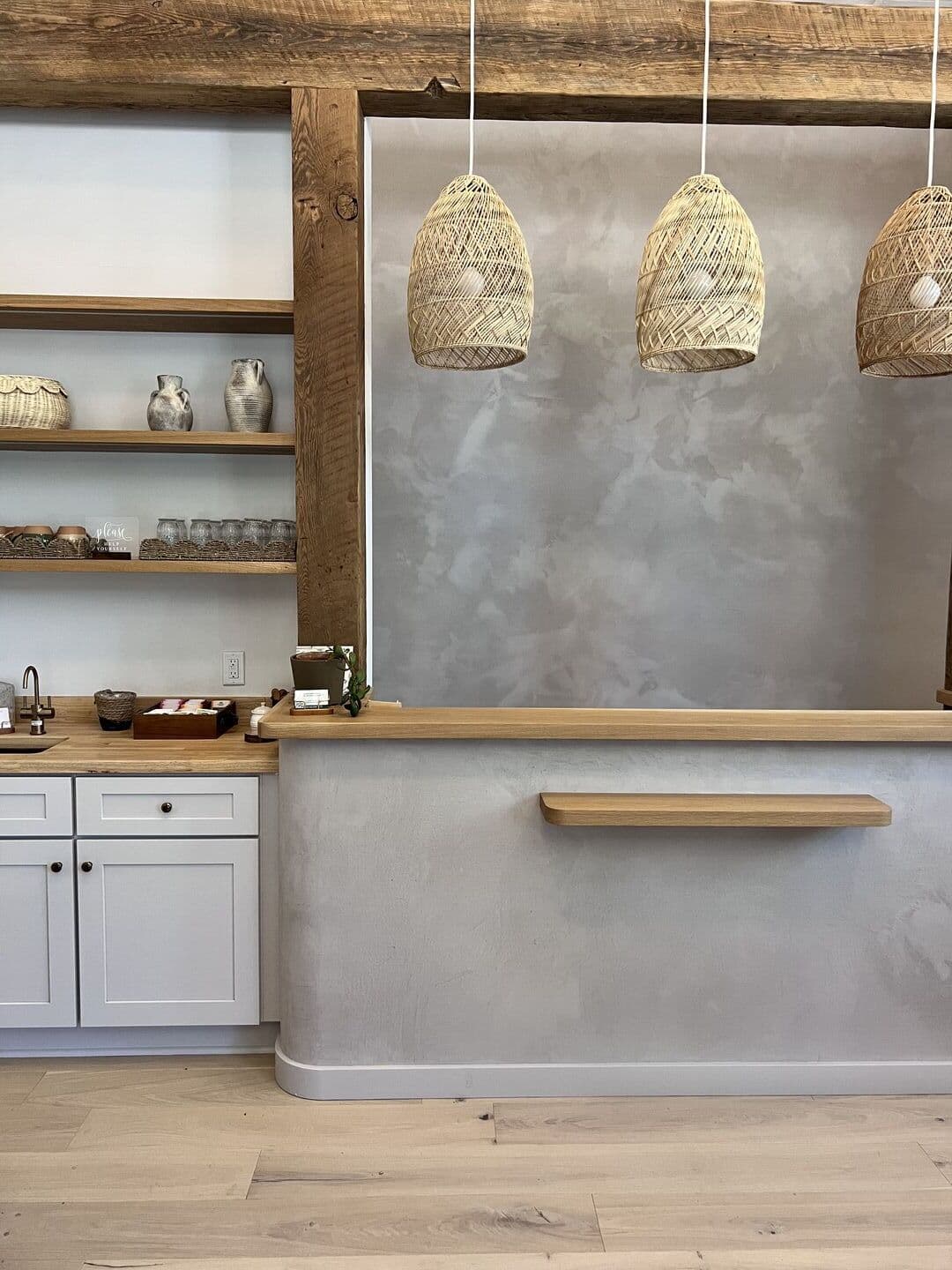 Kitchen with grey plaster wall and woven pendant lights