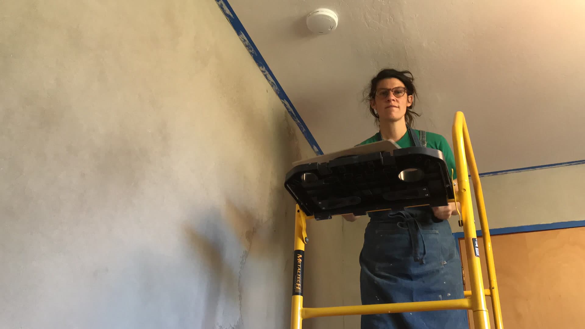 Marissa on a ladder applying plaster